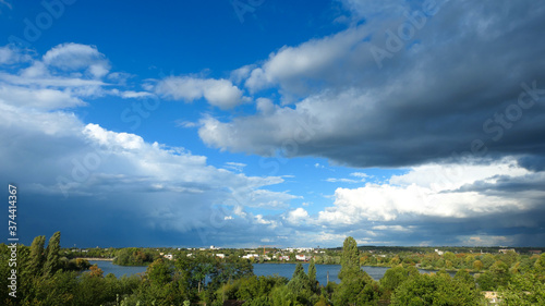Blue sky with cumulonimbus over the water. Beautiful landscape at the countryside. Sunny day with view on a lake.Cloudy weather turning rainy. 