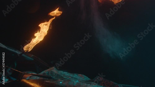 Fire show artist breathes fire in a wrecked car, dump of cars, slow mo