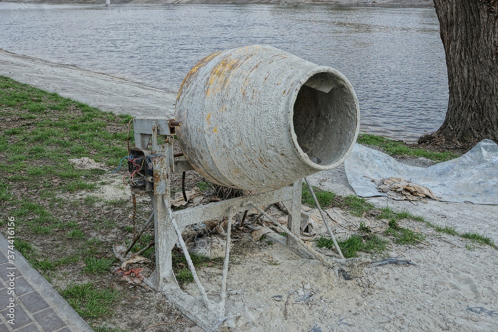 one old dirty concrete mixer stands on the street on the shore of the reservoir one old dirty concrete mixer stands on the street on the shore of the reservoir