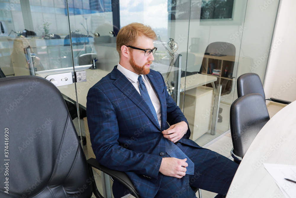 a red bearded man sits relaxed at a table in the meeting room