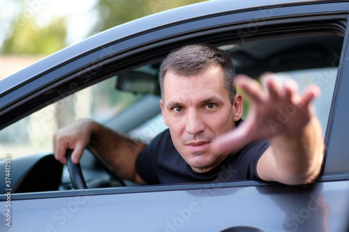 Aggressive and angry white man driving car. Boor on the road. Concept of politeness and relationship on the road.