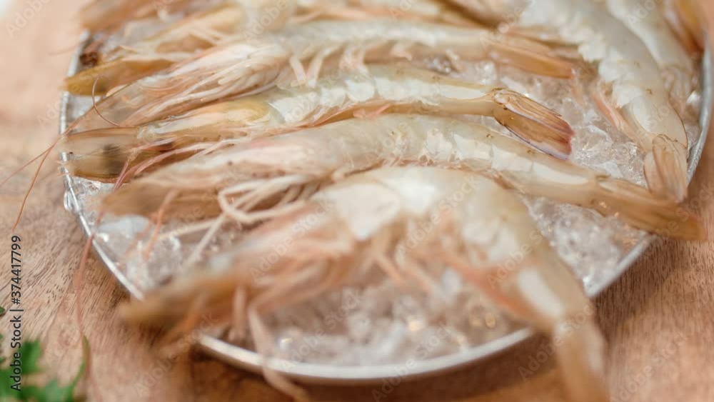 A close-up look of fresh raw shrimps/prawns in a tray with crushed ice in 4K.