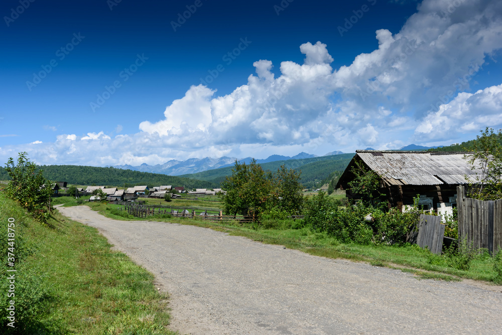 Old Russian village in Buryatia lying in the Tunkinskaya valley with mountain and clouds in summer day Old Russian village in Buryatia lying in the Tunkinskaya valley with mountain and clouds in summer day