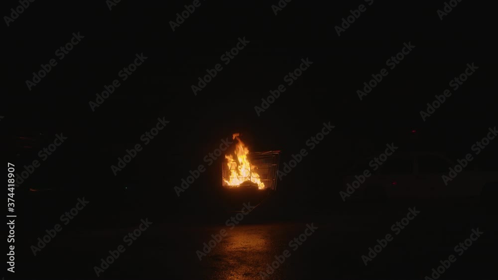 The shopping cart is on fire, in dump of car, dark night, slow mo The shopping cart is on fire, in dump of car, dark night, slow mo