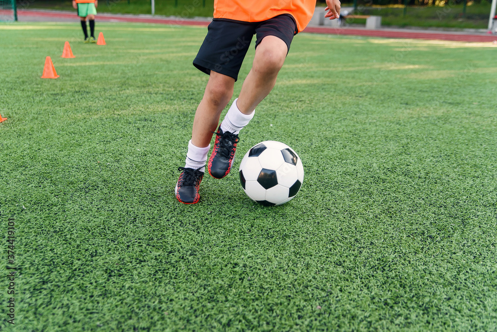 Soccer player kicking ball on field. Soccer players on training session. Close up footballer feet kicking ball on grass. Soccer player kicking ball on field. Soccer players on training session. Close up footballer feet kicking ball on grass.