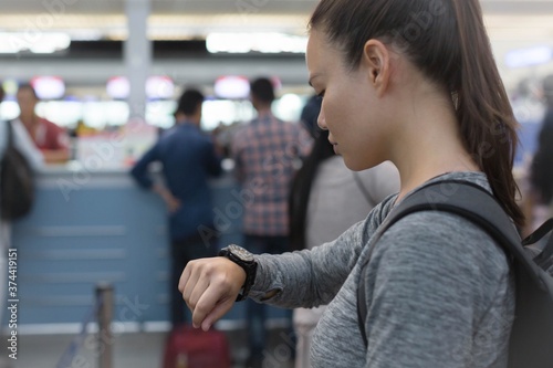 Quadro su tela A woman checking the time at the airport, standing in line at the ticket check in counter