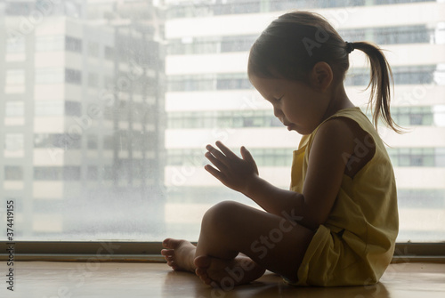 A little girl sitting down in prayer at home. Religious people. Free Download A little girl sitting down in prayer at home. Religious people. - GFXLoad