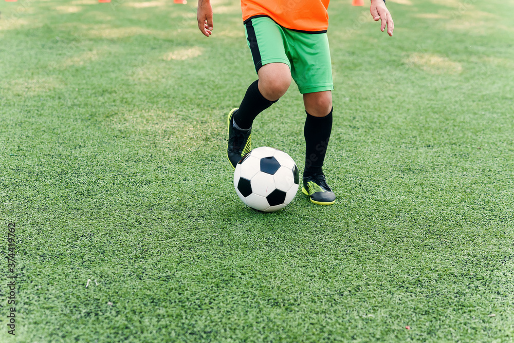 Soccer player kicking ball on field. Soccer players on training session. Close up footballer feet kicking ball on grass. Soccer player kicking ball on field. Soccer players on training session. Close up footballer feet kicking ball on grass.