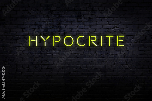 Photos Neon sign. Word hypocrite against brick wall. Night view