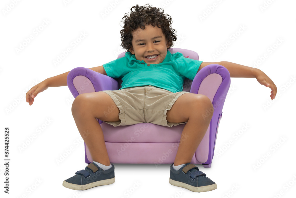 A happy toddler sits on a whimsical kids chair with arms hanging over the side and open legs. The curly hair boy smiles at the camera, photographed on a white background. A happy toddler sits on a whimsical kids chair with arms hanging over the side and open legs. The curly hair boy smiles at the camera, photographed on a white background.