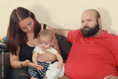 Mamá mexicana carga a bebe en casa junto a su esposo photo