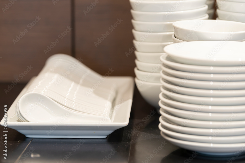 Obraz premium A lot of white clean plates ready to serve. Different types of dishes and Asian ceramic spoon for soup or liquid food. Selective focus 