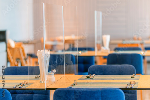 Social distancing at Restaurant. Seat for customers sitting separated in restaurant with table shield plastic partition to protect infection from coronavirus covid-19 photo