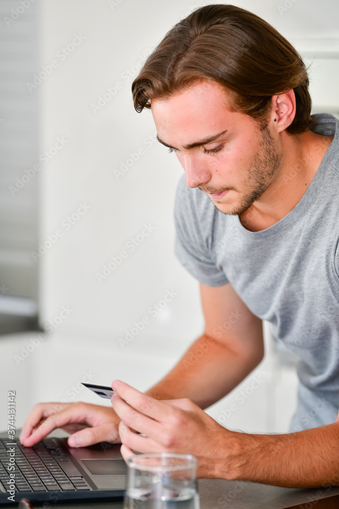 Close up of a handsome young man in the process of making an online payment using a credit card. Payment and online concept. Close up of a handsome young man in the process of making an online payment using a credit card. Payment and online concept.