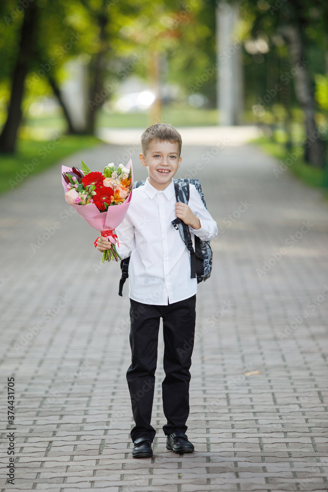 Fototapeta premium Schoolboy with flowers in a city park.