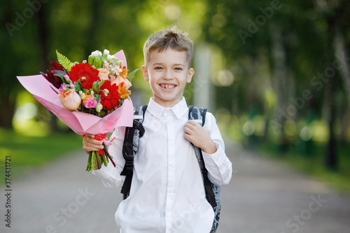 Schoolboy with flowers in a city park.