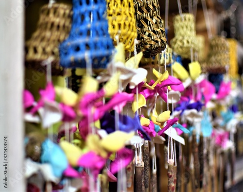 Traditional colorful rattan and sea shell wind chimes hang in an island souvenir shop