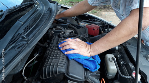 The hand of a male mechanic checking the engine. 
