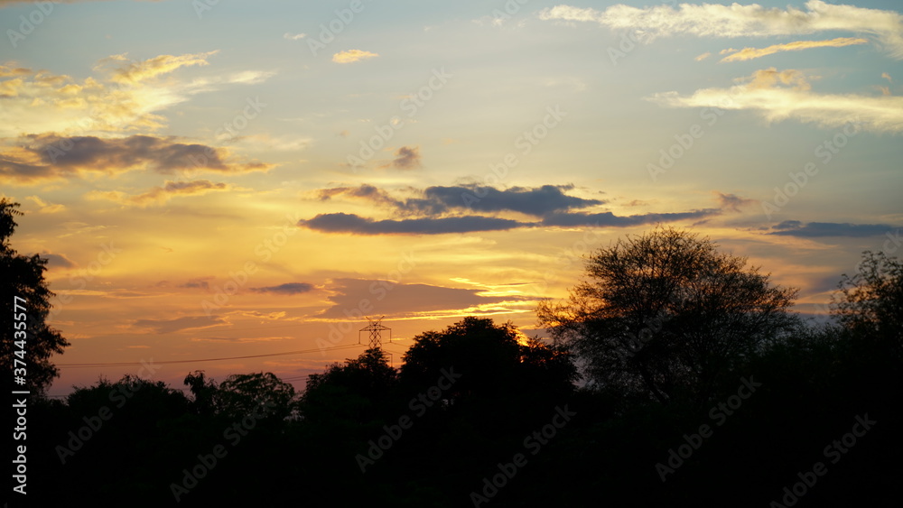 Beautiful sunset sight, golden hovering clouds. Red sunset rays,evening panorama, colorful rays at sky. An enchanting moment of nature.
