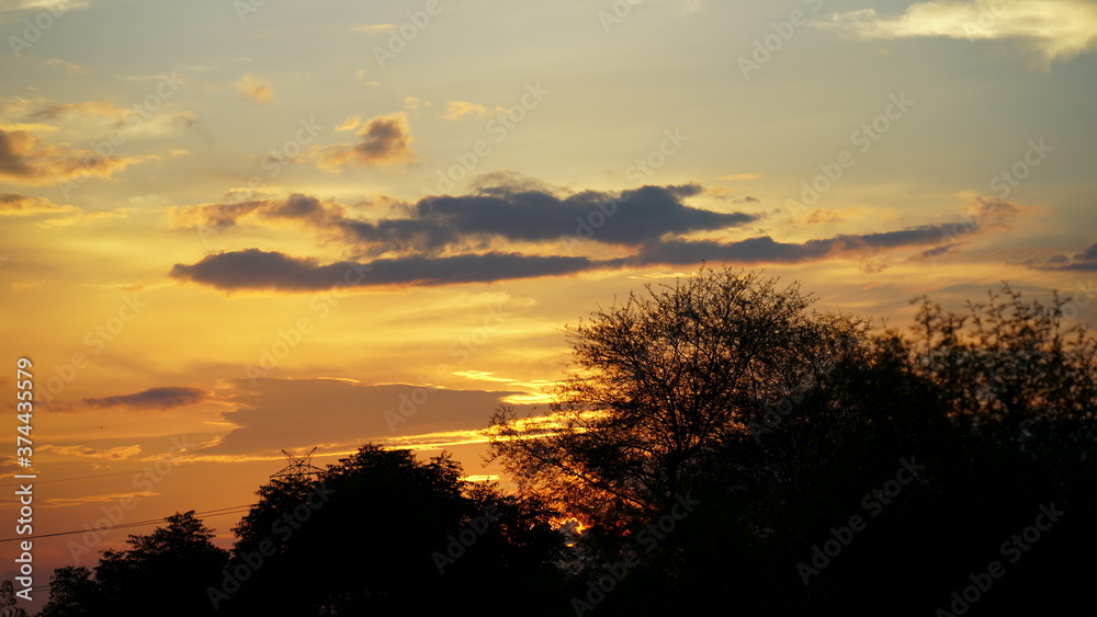 Beautiful sunset sight, golden hovering clouds. Red sunset rays,evening panorama, colorful rays at sky. An enchanting moment of nature.
