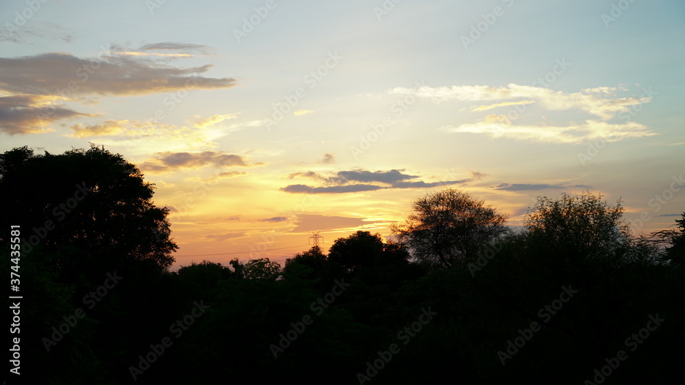Obraz premium Beautiful sunset sight, golden hovering clouds. Red sunset rays,evening panorama, colorful rays at sky. An enchanting moment of nature. 