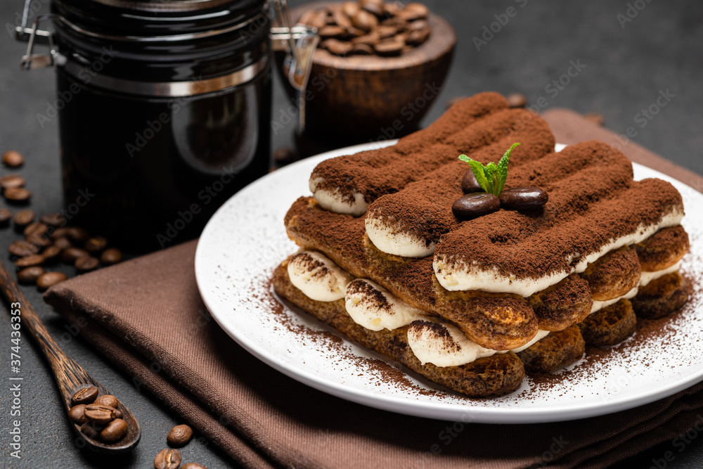 Classic tiramisu dessert and coffee grinder on ceramic plate on concrete background Classic tiramisu dessert and coffee grinder on ceramic plate on concrete background