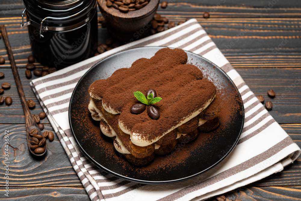 Classic tiramisu dessert and coffee grinder on ceramic plate on wooden background Classic tiramisu dessert and coffee grinder on ceramic plate on wooden background