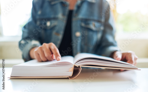 Closeup image of a woman sitting and reading book at home