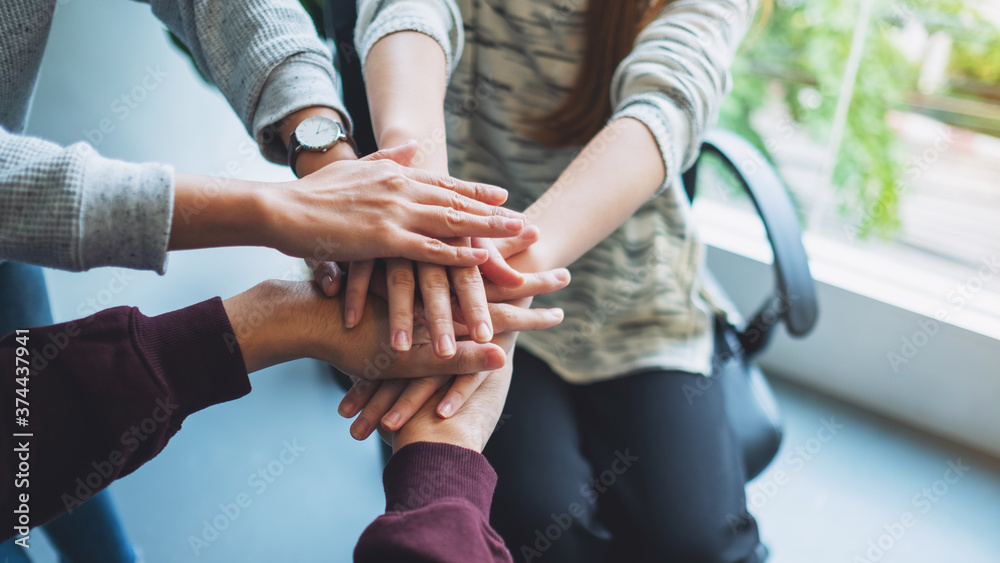 Closeup image of business team standing and joining their hands together in office Closeup image of business team standing and joining their hands together in office