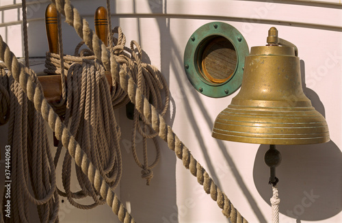 Isolated close up of old sailboat's rope lines, porthole and brass bell