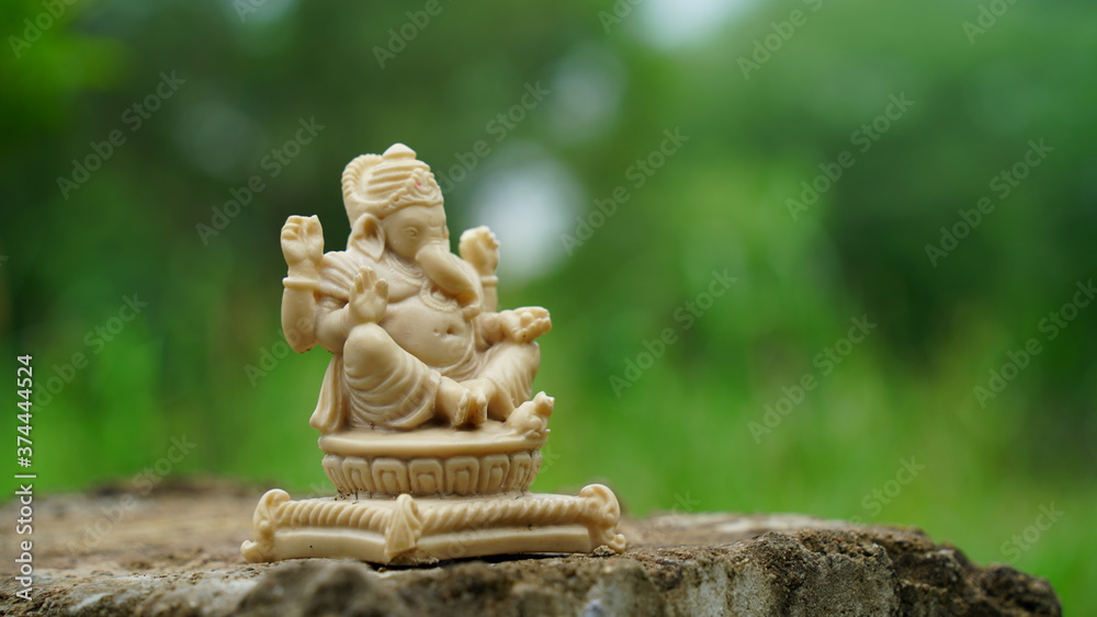 Obraz premium White idol of Lord Ganesha or Ganpati with blurred background. Marble statue isolated on column. 