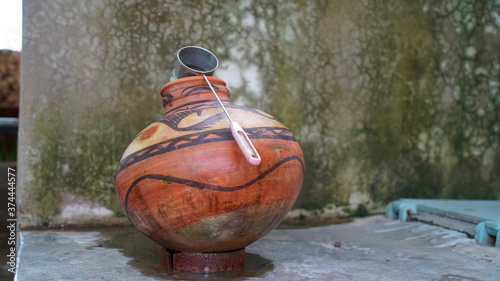 Red Clay pot with stainless steel glass in a house corner. Stylish printed art, ancient India culture to make pot.  © Asha