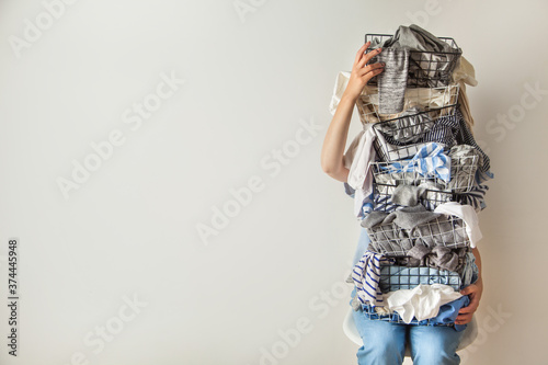 Canvas Print Surprised woman holding metal laundry basket with messy clothes on white background