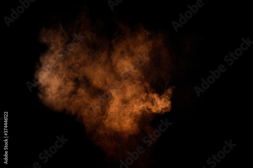 Orange powder explosion on black background. Colored powder cloud. Colorful dust explode. Paint Holi. © sergio34
