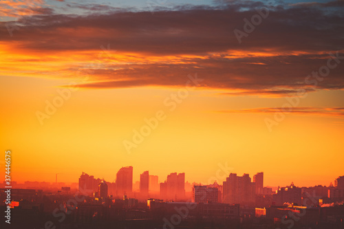 Sunset aerial Europe town silhouette: Kyiv cityscape at sun set golden tones cloudy sky. Ukrainian capital urban architecture with high skyscrapers, houses, buildings. Majestic european scenery view