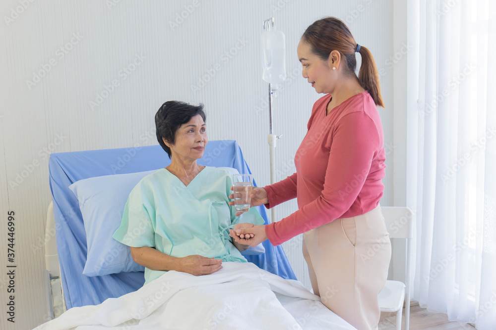 An elderly Asian woman is being taken care of by her relatives in the hospital recovery room.