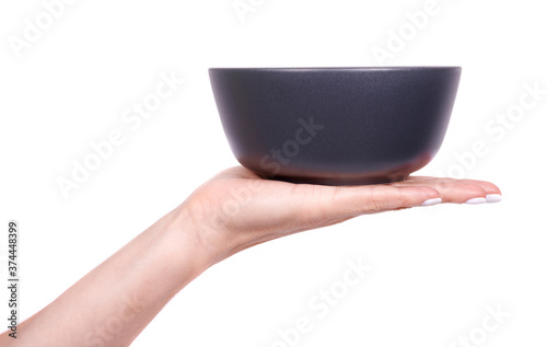 Hand with dark empty round bowl, ceramic kitchen dishware, isolated on white background.