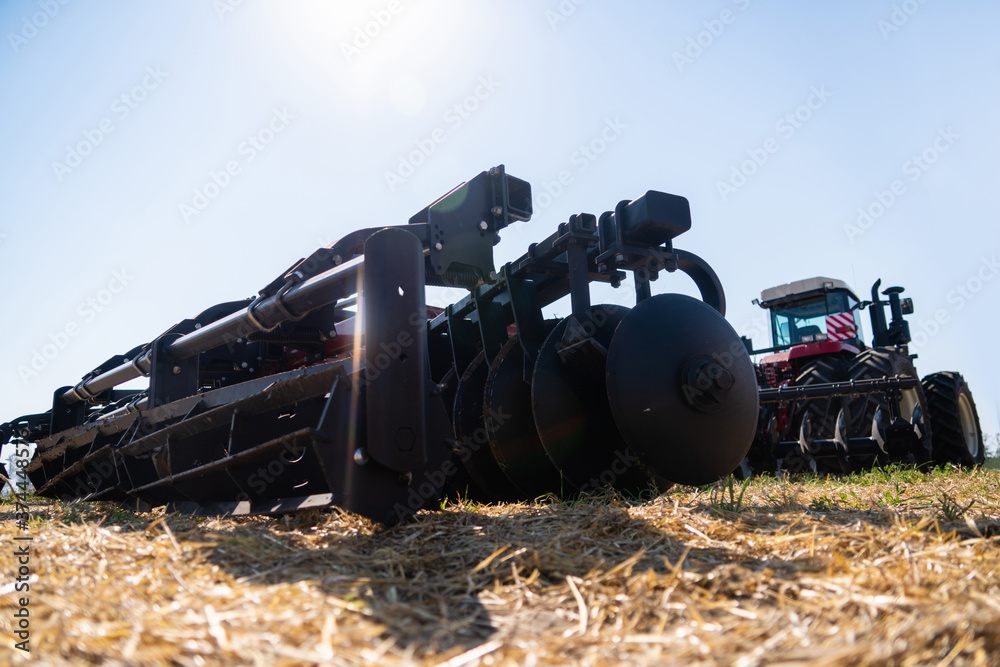 A tractor with a plow plows the field after harvesting A tractor with a plow plows the field after harvesting