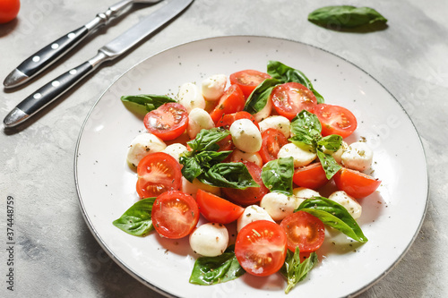 Traditional Italian Caprese Salad - sliced tomatoes, mozzarella cheese and basil on concrete background