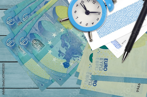 20 euro bills and alarm clock with pen and envelopes. Tax season concept, payment deadline for credit or loan. Financial operations using postal service photo