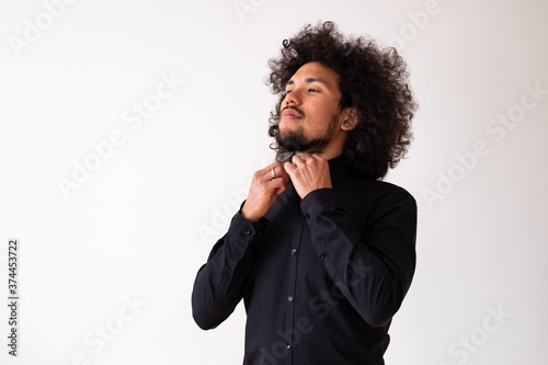 Latin American model in black shirt with big curly hair and beard, neutral background 