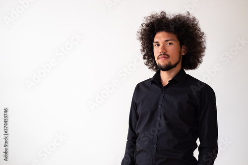 Latin American model in black shirt with big curly hair and beard, neutral background 