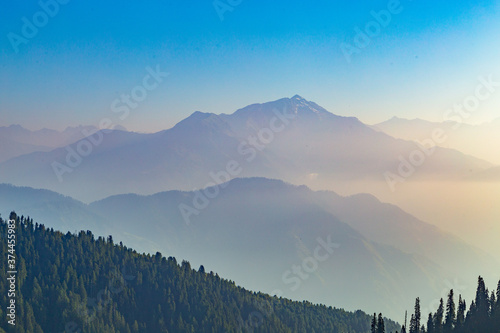 lush green mountain line and meadows landscape from the top hill with clear blue sky and forest © Safeer