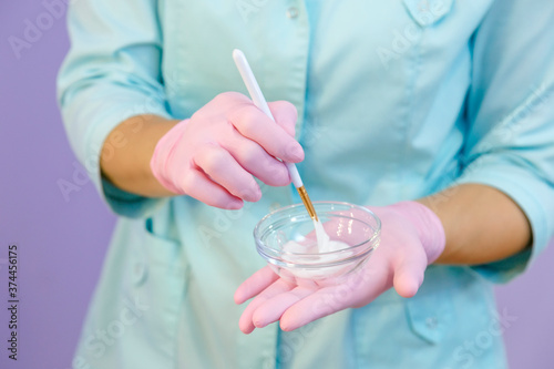 Female hands in pink gloves of a woman in uniform mixing white cream in a cup © bander