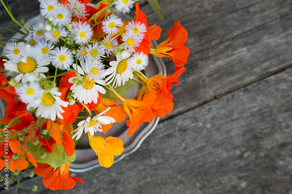 Bouquet of nasturtium and camomiles on an old wooden background