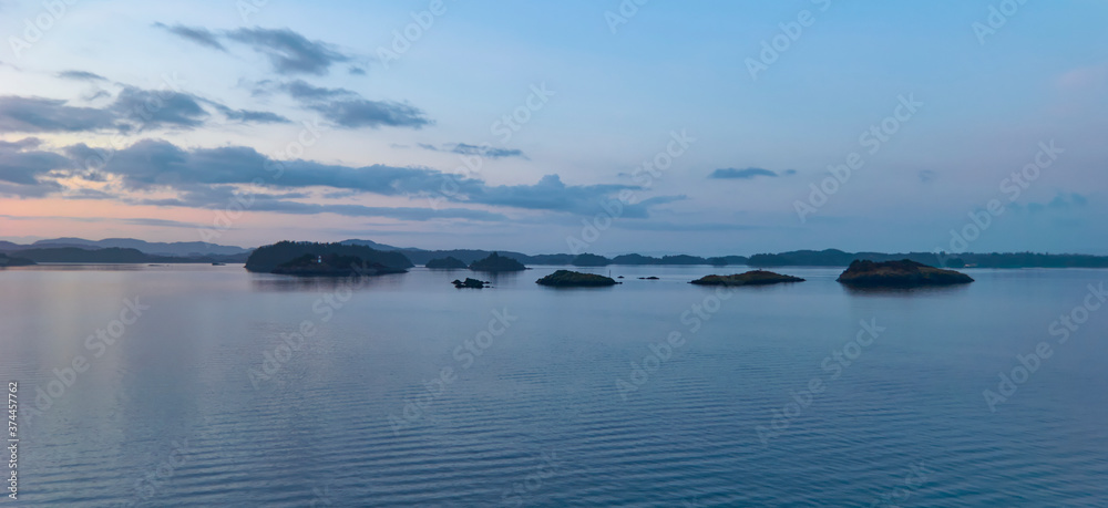 Small Islands being lit up in the dawn light of a new day on the way to Bergen through the Fjords on one cold Winters morning. Norway.