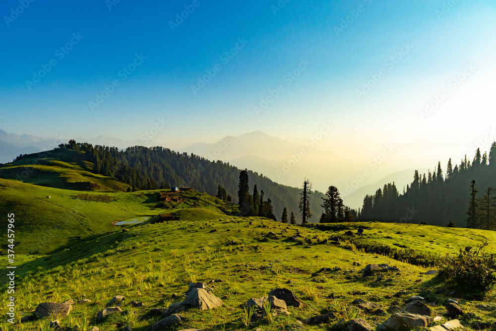Fototapeta premium lush green mountain line and meadows landscape from the top hill with clear blue sky and forest 