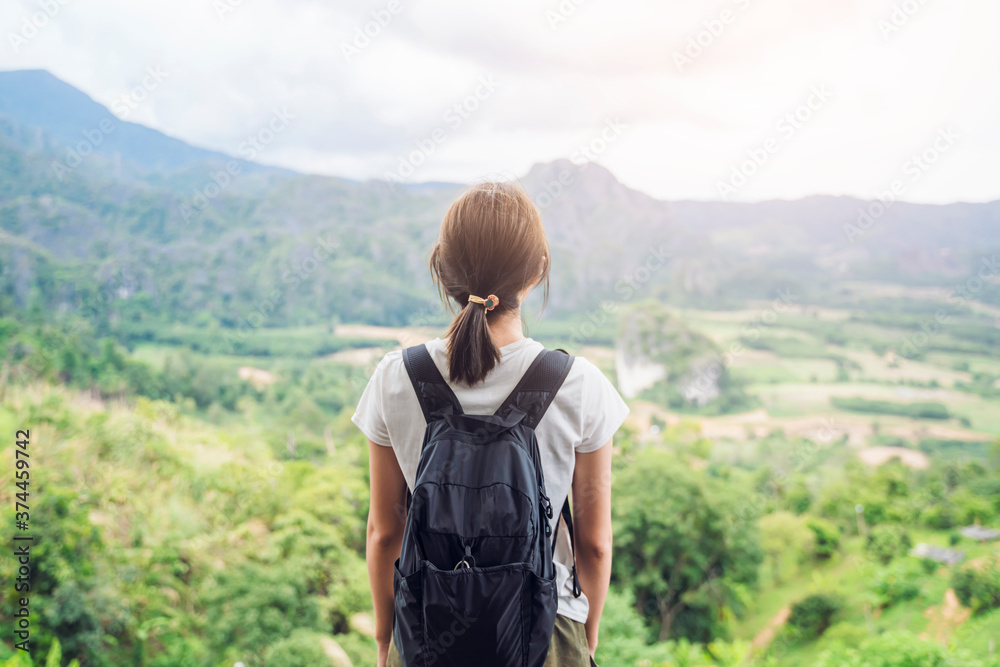 Asian attractive young woman traveler tourist hiking bag pack hipster standing silhouette looking at mountain valley nature landscape view scenery hot summer wearing hat feeling peaceful joyful happy
