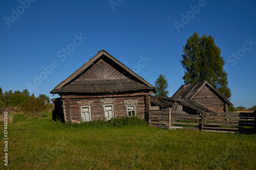 A large beautiful wooden two story abandoned farm house with peeling paint and broken windows in a rural summer countryside
