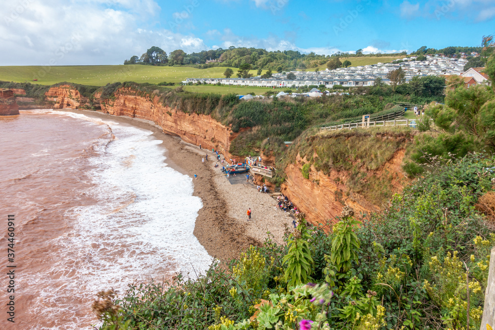 Waves breaking onto the beach at Ladram Bay near Exmouth in South Devon, England, UK. Red sandstone cliffs, part of the Jurassic Coast.
